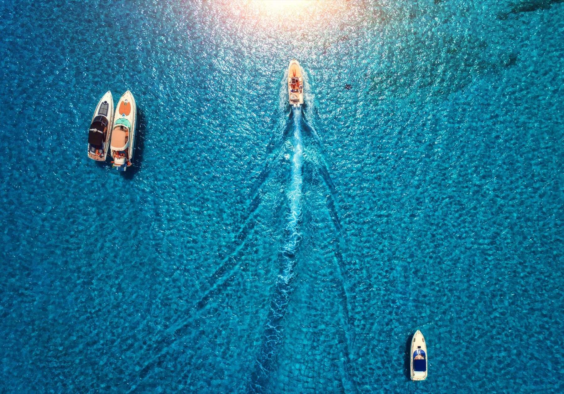 Two motor yachts crossing clear blue water seen from above