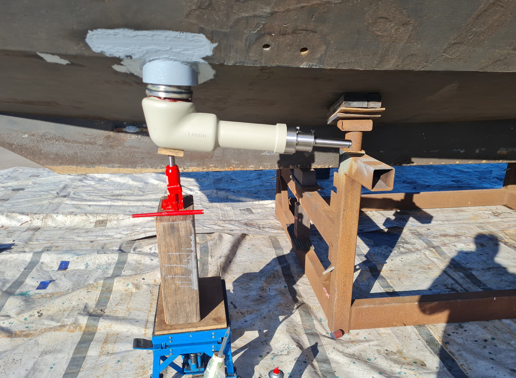 The cream rotor drive of a RotorSwing system freshly fitted through the steel hull of MY Sytske, held on a jack while the yacht stands on yard cradles