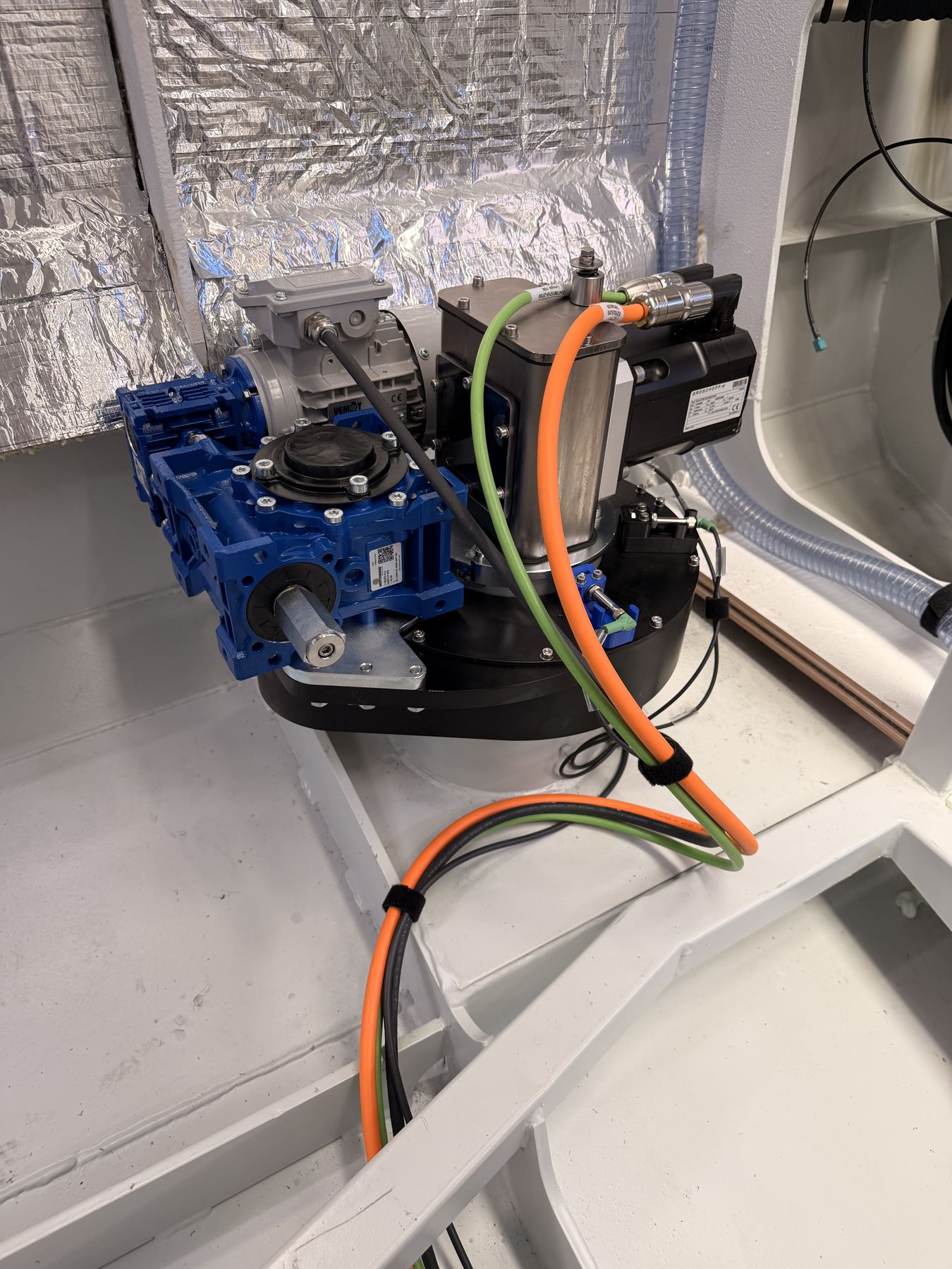 A drive unit installed in an insulated compartment, orange and green cabling running down to the gearbox