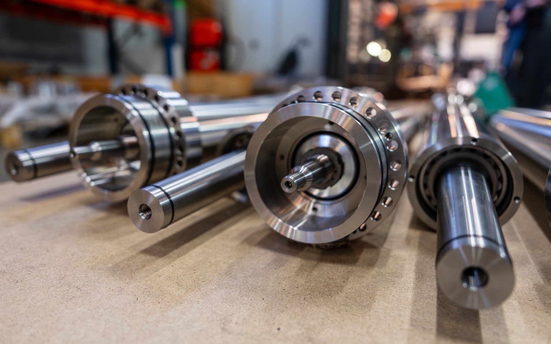 Machined stainless drive shafts with flanged bearing housings on a workshop surface at the RotorSwing factory