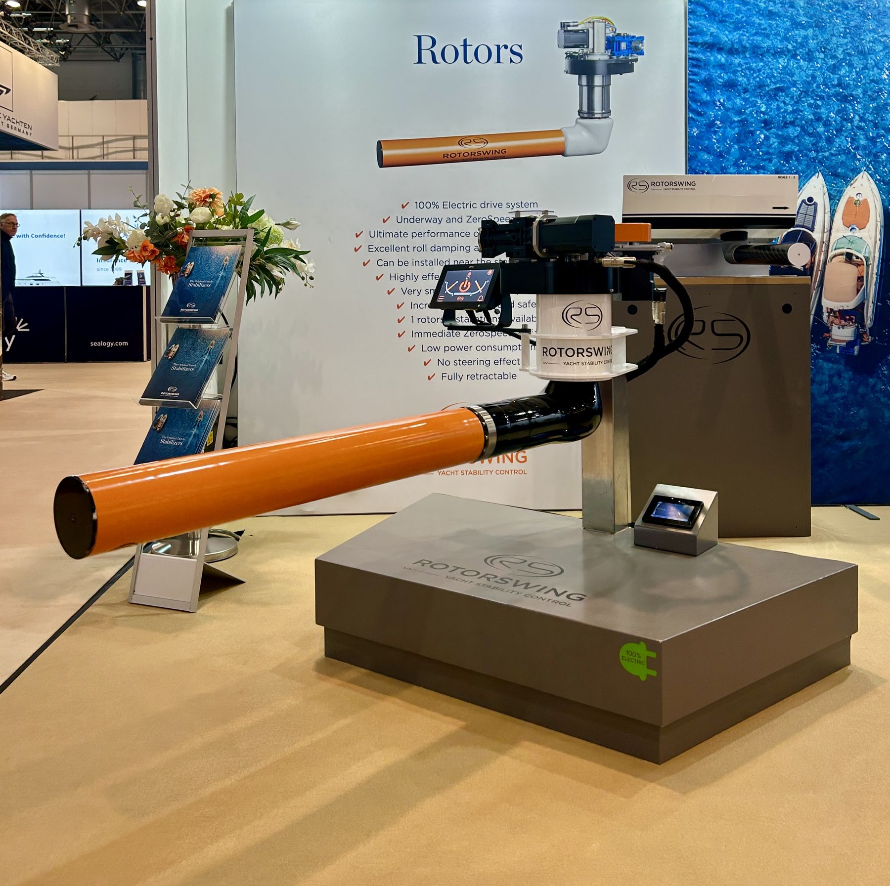 The RotorSwing stand at Boot Dusseldorf: an orange rotor cylinder and drive head on a plinth, in front of a panel listing what the system does