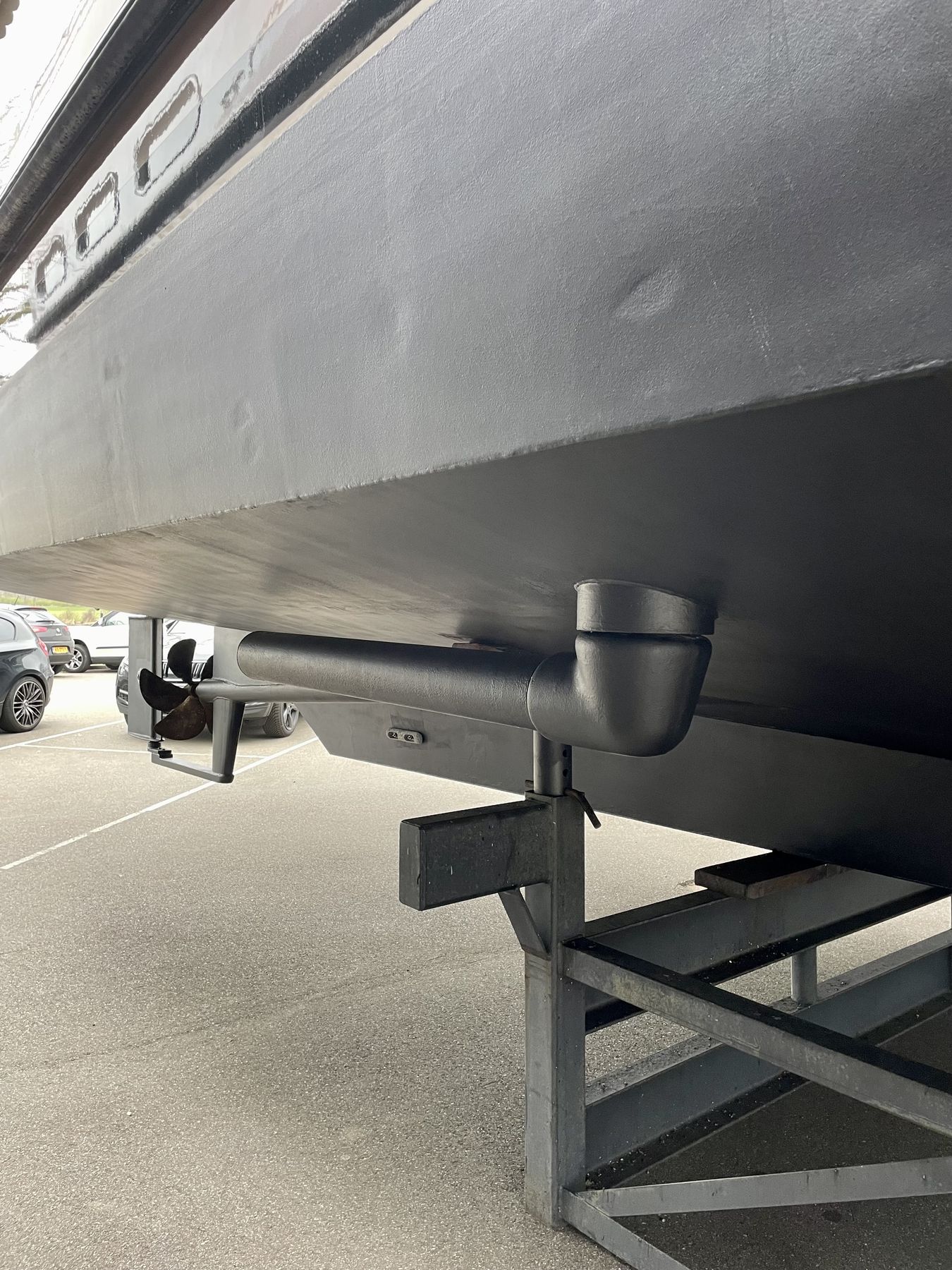 A hull ashore on stands with the rotor arm folded against the plating, seen from below