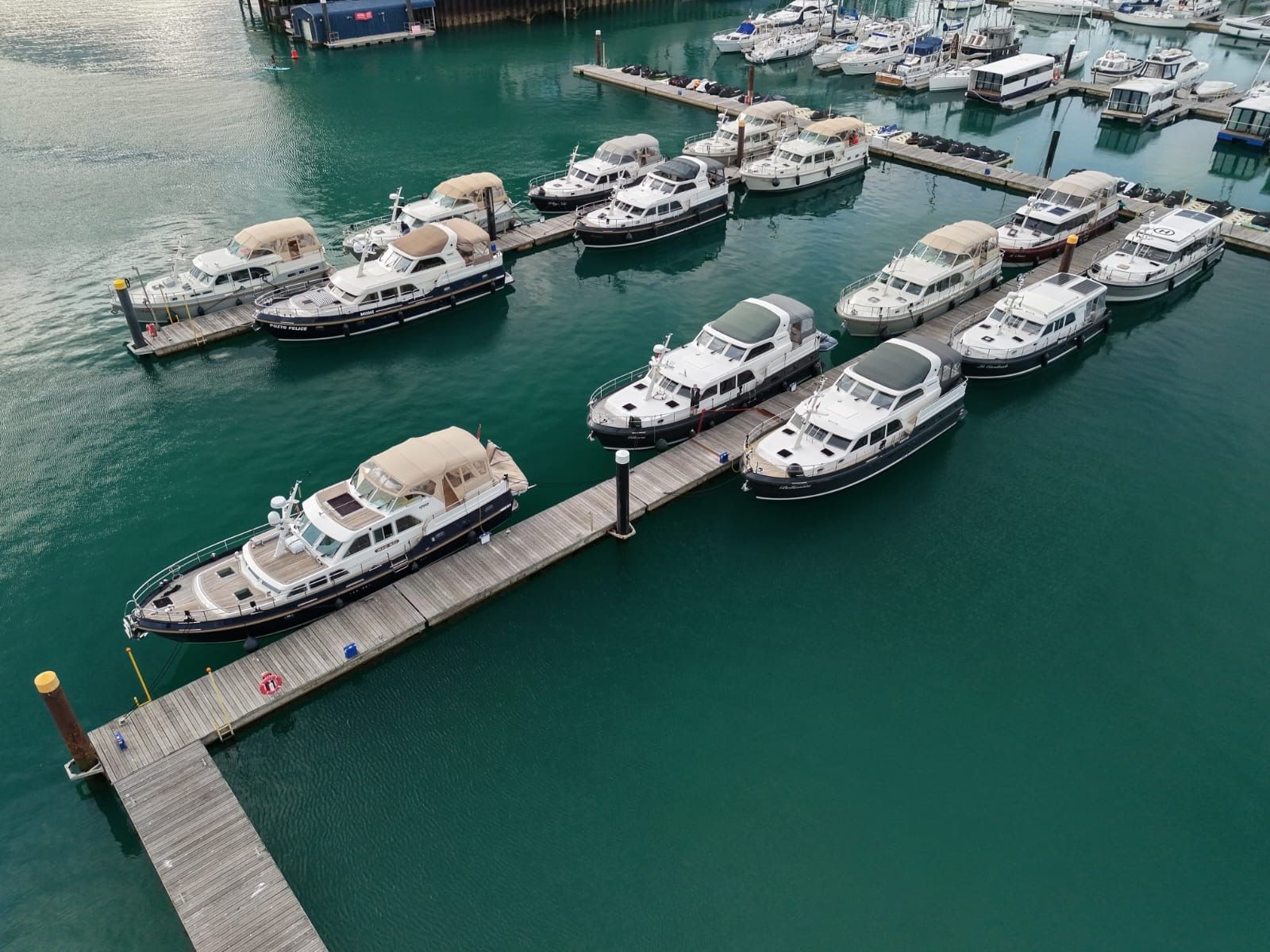 A marina seen from above: motor yachts of the same class moored side by side along wooden pontoons