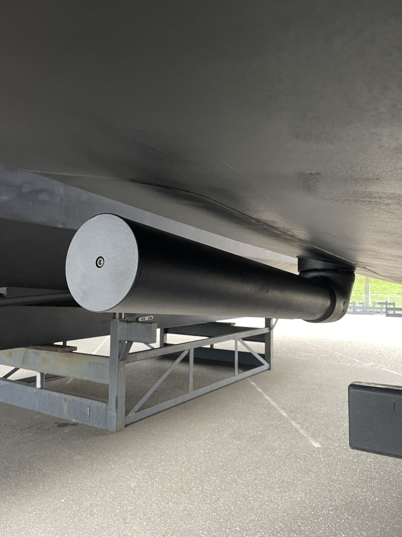 A rotor deployed under a hull ashore, its round end cap facing the camera above the galvanised stands