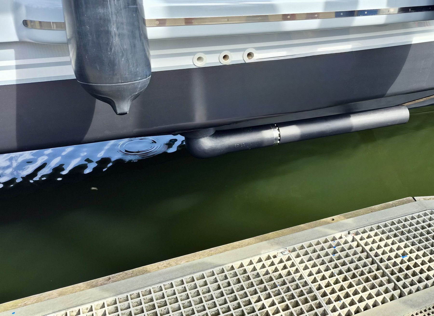 A RotorSwing rotor stowed horizontally against a dark hull just above the waterline, seen from the pontoon alongside