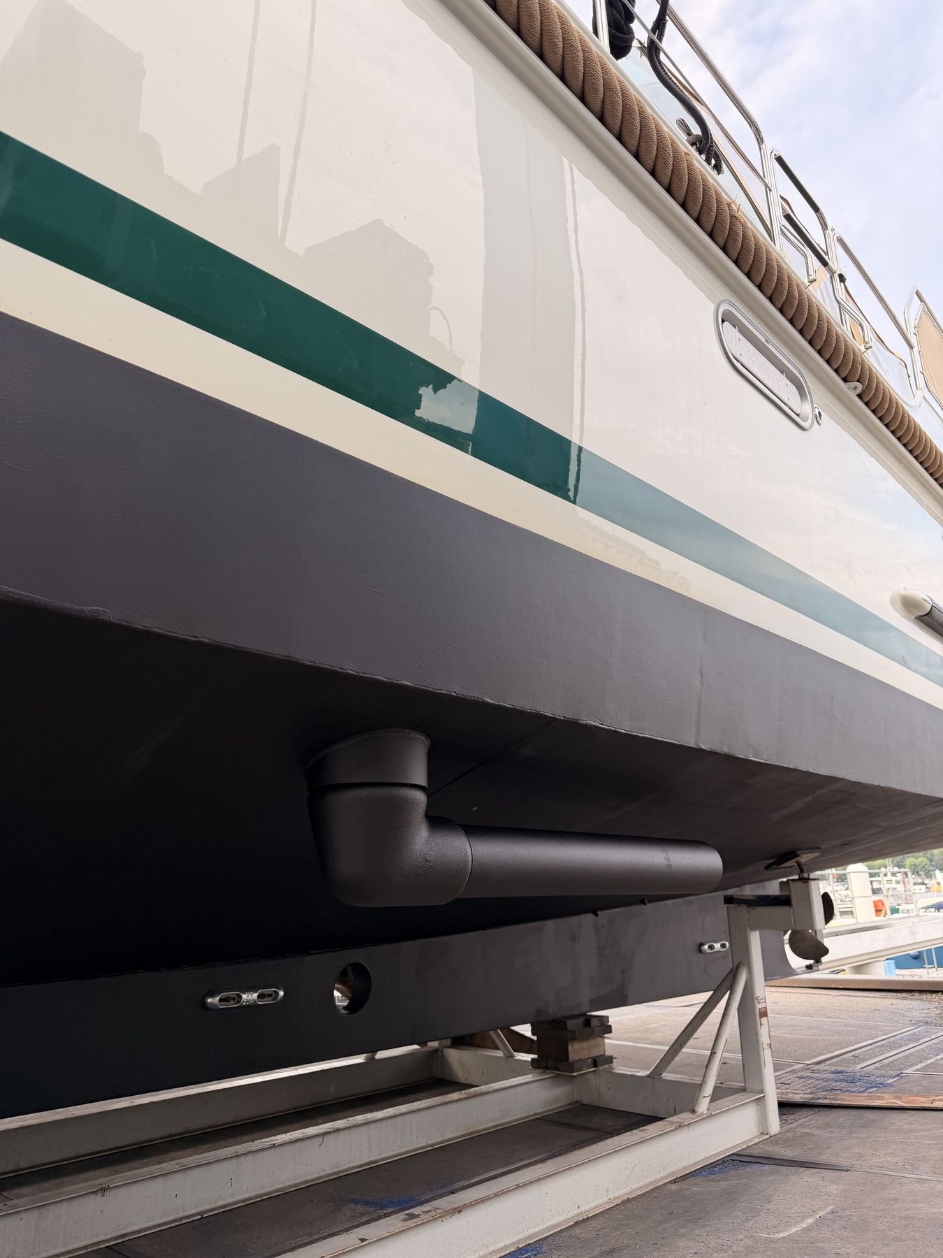 A rotor stowed along a white hull with a green sheerline, the yacht resting in its cradle